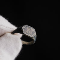 Gloved hand holding medieval silver ring Radomir, close view of engraved bezel detail