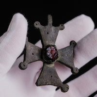 Hand holding Medieval bronze cross 'Gemmata' showing scale and paired knob terminals of the arms.