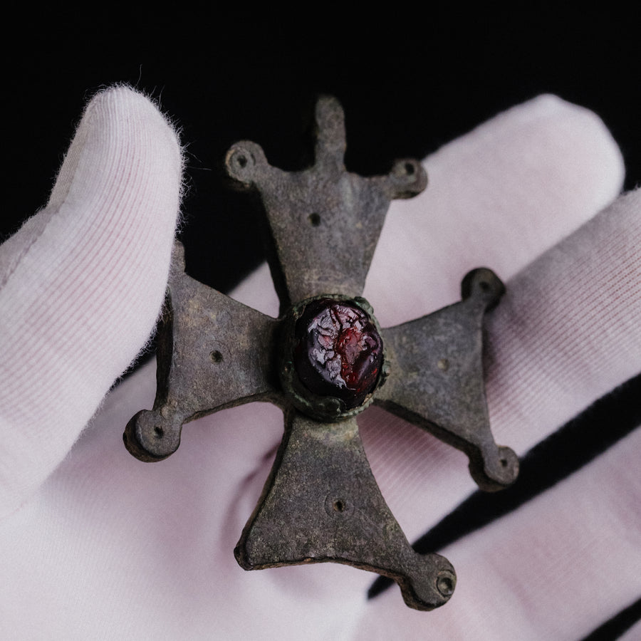 Hand holding Medieval bronze cross 'Gemmata' showing scale and paired knob terminals of the arms.