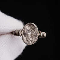 Roman silver ring Veneria held in gloved fingers, close view of the plate engraved with a draped bust