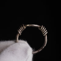 Roman silver ring Veneria held in a gloved hand, showing the round hoop and coiled wire shoulders