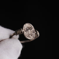 Roman silver ring Veneria held in gloved fingers, angled view of the intaglio plate and coils