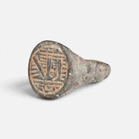 Medieval Islamic bronze ring 'Tahir' shows its angular bezel engraving from the opposite front angle.
