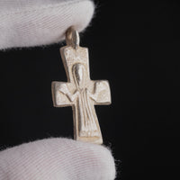 Macro close-up of Peristeria Byzantine silver cross pendant showing orant figure and drapery folds