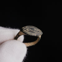 Macro detail of medieval bronze signet Radulf bezel engraving held in gloved hand