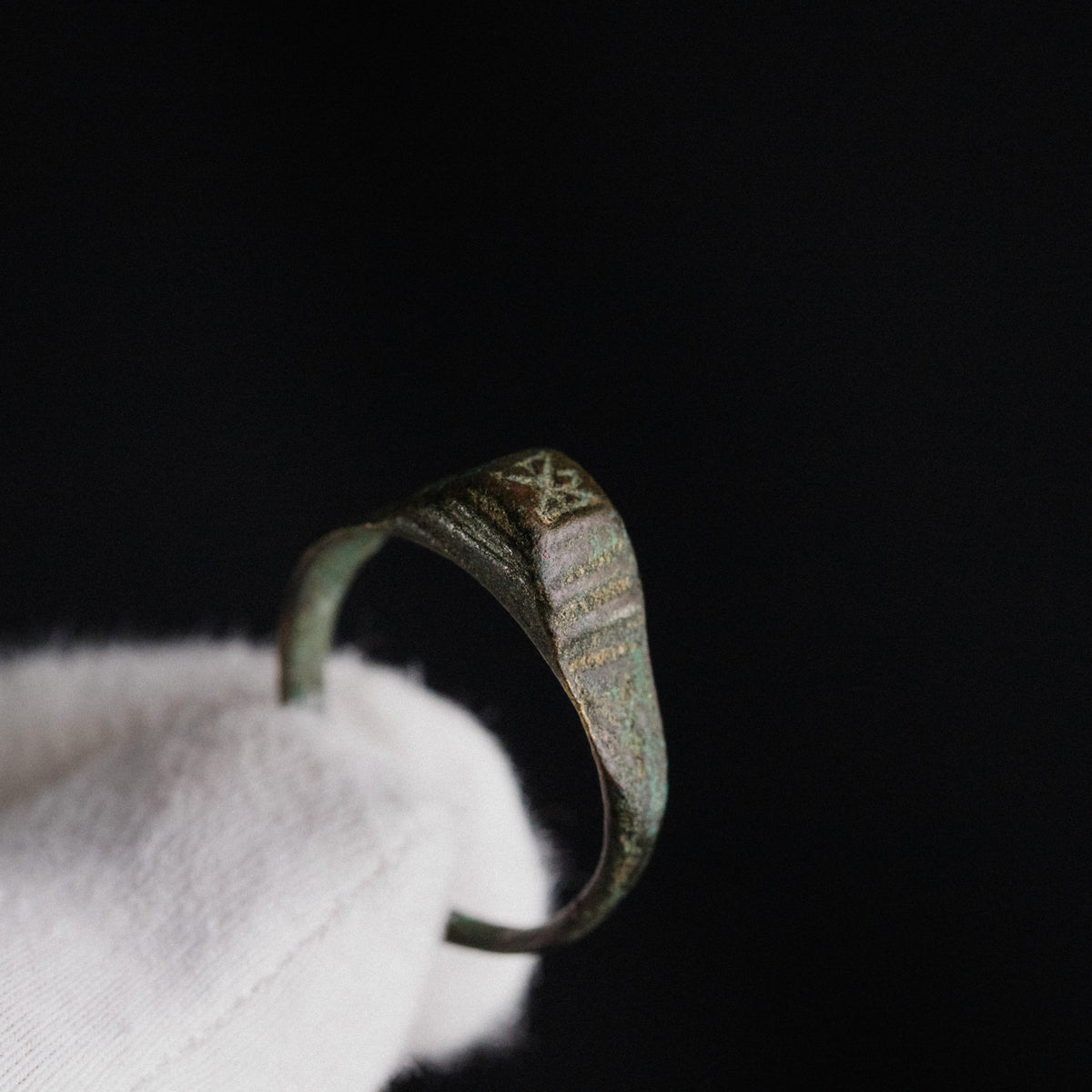 Macro view of Roman bronze ring Numerius shoulder engraving against dark background