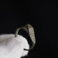 Macro view of Roman bronze ring Numerius shoulder engraving against dark background