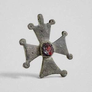 Medieval bronze cross pendant 'Gemmata' with flaring arms, paired knob terminals and a red cabochon at the centre.