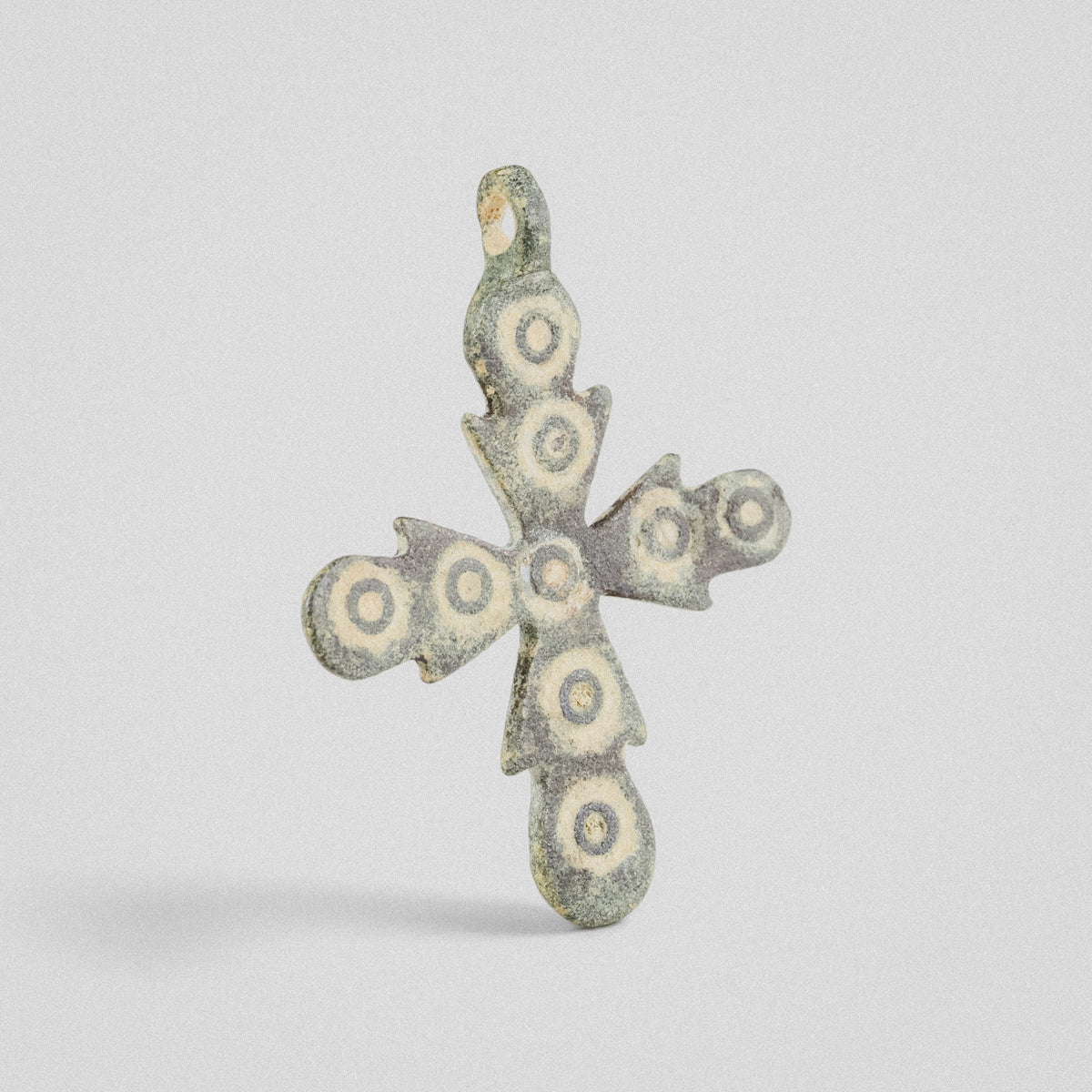 Medieval bronze cross pendant 'Rotunda' shown at an angle, ring-and-dot ornaments and cast suspension loop
