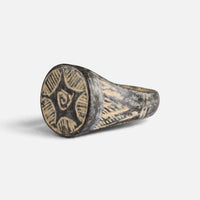Medieval bronze ring 'Aldebrand' shows its hatched circular bezel decoration from the opposite front angle.