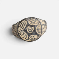 Medieval bronze ring 'Aldebrand' shows hatched bezel segments surrounding a small central curled mark.