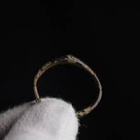 Medieval bronze ring Alderic held in gloved hand on black background, side detail