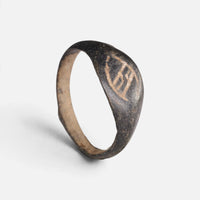 Medieval bronze ring 'Arnulf' shows its angular incised bezel mark and complete hoop at an angle.