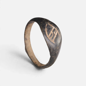 Medieval bronze ring 'Arnulf' shows its angular incised bezel mark and complete hoop at an angle.