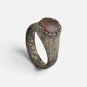Medieval bronze ring 'Radwina' shows its round reddish setting and engraved shoulder from another angle.