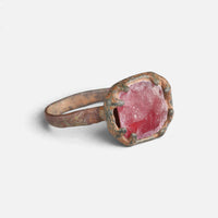 Medieval bronze ring 'Rutheris' shows its red setting and surrounding metal tabs at an angle.