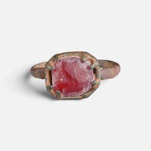 Medieval bronze ring 'Rutheris' shows the red face of its setting from the front.