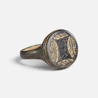 Medieval bronze ring 'Ventaris' shows its leaf-like bezel engraving and broad shoulder at an angle.