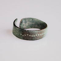 Medieval bronze ring Vesna at an angle, highlighting flowing incised lines across the band
