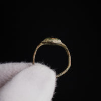 Medieval bronze ring Vespertin held in gloved hand, silhouette against black background