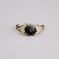 Medieval bronze ring Vespertin with dark glass paste cabochon in oval cup bezel, top view