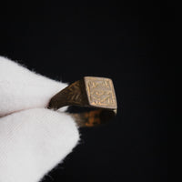 Medieval bronze signet ring Aldric in gloved hand, angled view of engraved device