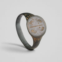 Medieval bronze signet ring Lioris with mirrored scroll bezel, three-quarter view