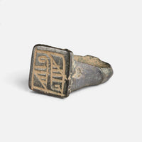 Medieval Islamic bronze ring 'Rashida' shows its rectangular bezel engraving from the opposite front angle.