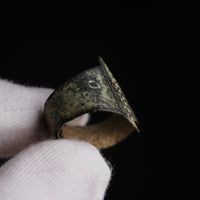 Medieval bronze ring Wistanoc, held in a gloved hand, showing a punched shoulder annulet and the bar edge