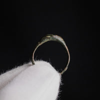 Medieval bronze ring Radenko standing on a gloved fingertip, profile of the band