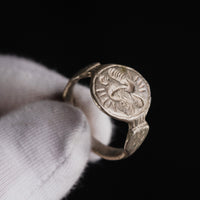 Medieval silver ring Wistrid held in a gloved hand, angled view of the S-whirl bezel