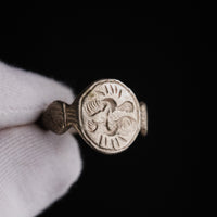 Medieval silver ring Wistrid held in a gloved hand, face-on view of the S-whirl intaglio