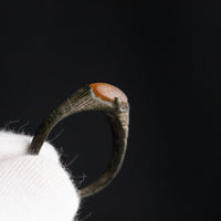 Medieval bronze ring Vukmir on a gloved fingertip, three-quarter view of bezel and incised shoulders