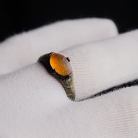 Medieval bronze ring Vukmir resting on a gloved hand, top view of the orange cabochon