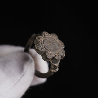 Medieval bronze ring Rosalind held in a gloved hand, oblique view of the scrolled lobes and shoulder collar