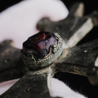 Angled close-up of the red cabochon and raised collet on medieval bronze cross pendant 'Gemmata'