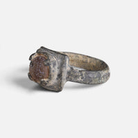 Medieval bronze ring 'Aldonza' shows its reddish setting from the opposite front angle.