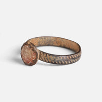 Medieval bronze ring 'Luminara' shows its pale setting and band decoration from the opposite front angle.