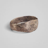 Silver band ring 'Ovata' shows its concentric oval engraving and shoulder fields from a low angle.