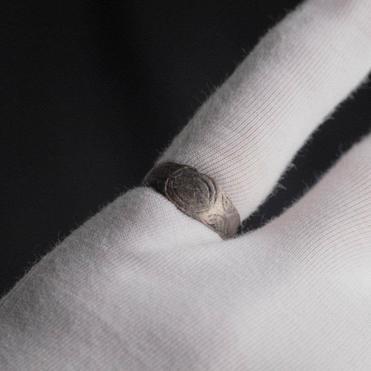 Silver band ring 'Ovata' shows its oval engraving while worn on a white-gloved finger.