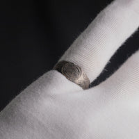Silver band ring 'Ovata' shows its oval engraving while worn on a white-gloved finger.