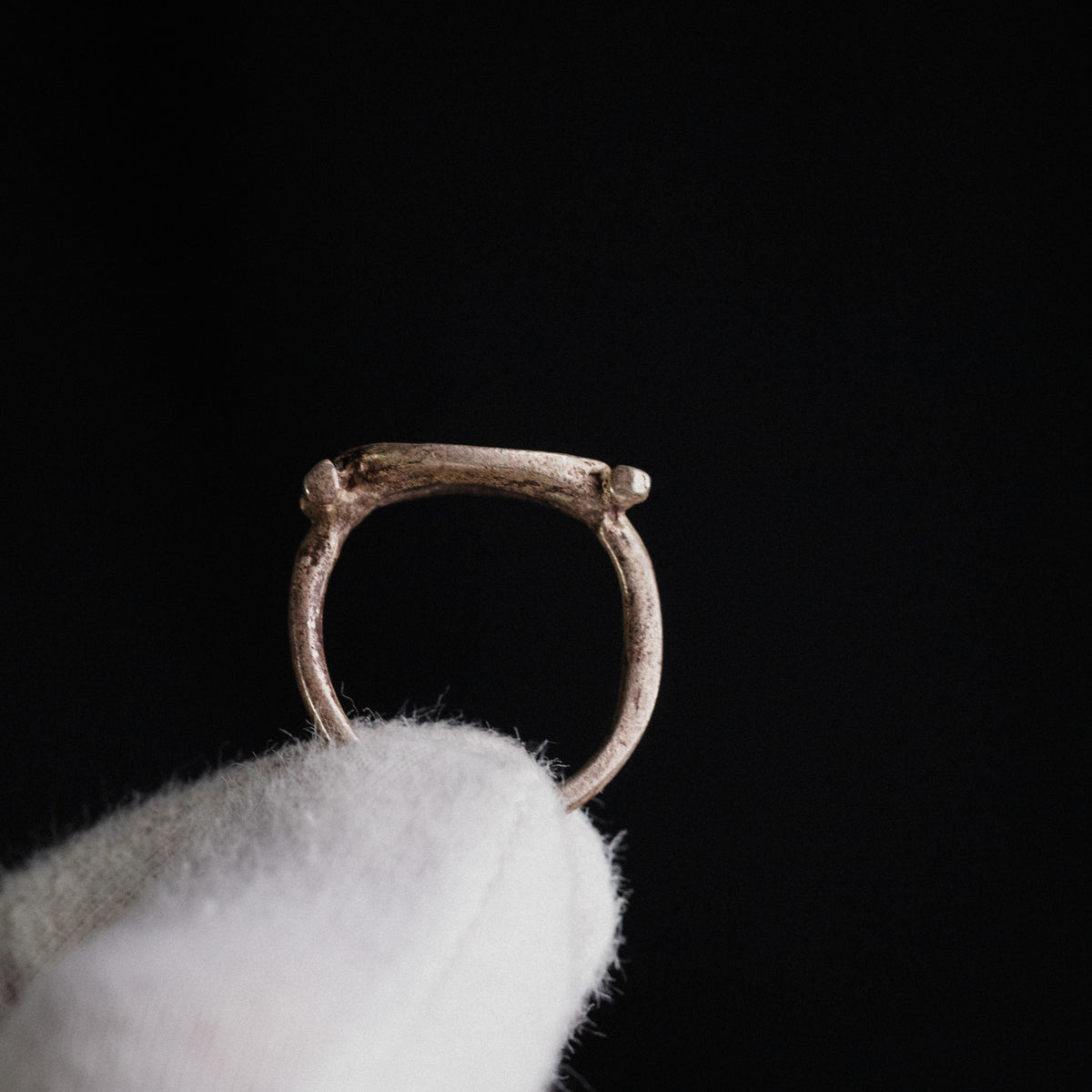 Profile of Roman silver ring Numeria on gloved hand showing swivel-bezel axis and shoulder bars