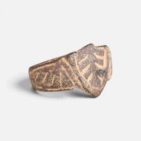Medieval bronze ring 'Radbert' shows its shield-shaped bezel and decorated broad shoulder at an angle.