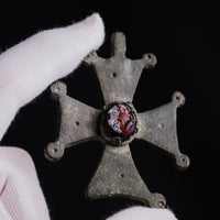 Reverse of Medieval bronze cross pendant 'Gemmata' held in hand, showing plain back and arm profiles.