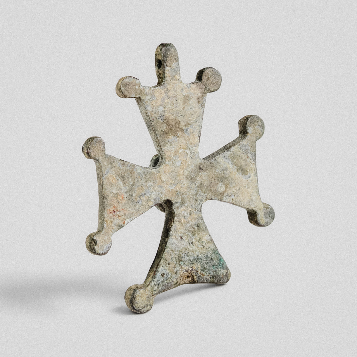 Reverse of Medieval bronze cross pendant 'Gemmata' showing plain plate and flat suspension lug at the top arm.