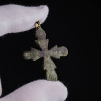 Reverse of Medieval bronze cross pendant 'Rotunda' held in a gloved hand, smooth bronze surface