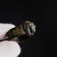 Roman bronze ring Leontios close-up on black, revealing lion muzzle and green patina
