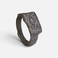 Roman bronze ring 'Lucina' shows its crossed geometric grooves and complete broad hoop at an angle.