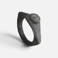 Roman bronze ring 'Hesperia' shows its small round bezel and complete angular hoop at an angle.