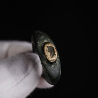 Roman bronze ring Vultinus held in a gloved hand, bezel face with engraved profile bust